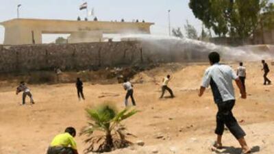 Egyptian security forces use a water cannon to disperse Palestinians throwing rocks at the Gaza Strip side of the Rafah border crossing with Egypt .