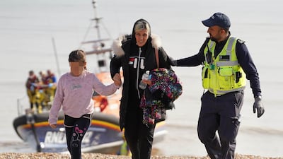 A woman and child are escorted into Dungeness after being picked up from a small boat in the English Channel on August 27, 2022. PA