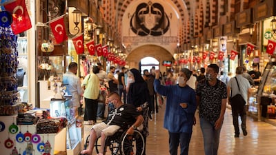 People wearing protective masks walk in the Grand Bazaar, in Istanbul. Moody's downgraded the country's rating due to weak finances and rising risks. AP.