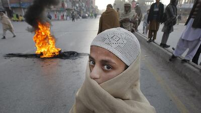A Pakistani religious student stands before a tire set on fire by anti-government protesters in Peshawar. Demonstrators are demanding the government unmask culprits of the Pakistan Taliban attack on a military-run school where more than a hundred children were killed on December 16, 2014. Mohammad Sajjad / AP Photo