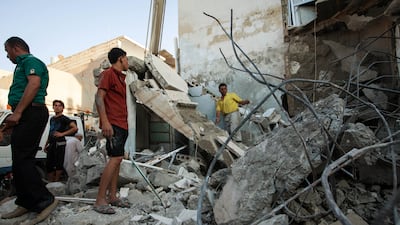 Syrians inspect debris after a bomb hit a building during clashes between rebel fighters and Syrian government forces on August 10, 2013 in the northern city of Raqqa. AFP