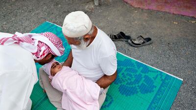 Ali Abdullah Ali Al Dhagmani holds his two month old son while Aid Mater kisses his forehead as a sign of respect and blessing. Ali and his family lives on a traditonal Emirate farm in Wadi Al Tuwa, Ras Al Khaimah.