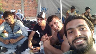 Iraqi Zaid Khalid Mahmood (right) is pictured with other refugees last August on the Macedonia side of the Macedonian-Greek border after having waited for ten hours to cross. The UN's refugee agency (UNHCR) provided them with food and water at this point. Courtesy Zaid Khalid Mahmood