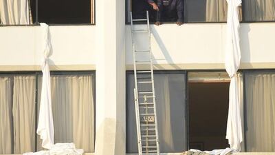 Pakistani fire fighters look from a room of Regent Plaza Hotel. AFP