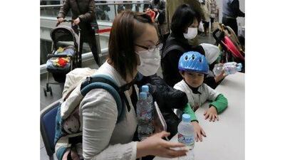 Mothers with children under 12 months receive bottles of water at a Tokyo ward office yesterday.