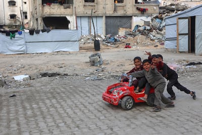 Palestinian children flashing V-for-victory signs while playing with a toy car near their displacement camp in Beit Lahia in the northern Gaza Strip. AFP