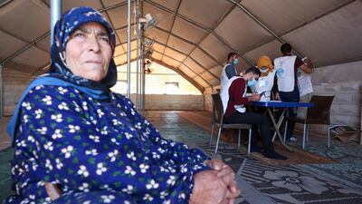 People wait as staff from the "Syria Immunization Group" NGO register patients with chronic diseases to receive the COVID-19 AstraZeneca vaccine at a camp for the internally displaced near Marret Misrin town, in the north of Syria's rebel-held Idlib governorate. AFP
