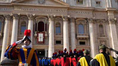 A Swiss guard salutes members of the Italian army marching towards St Peter's Basilica. AP