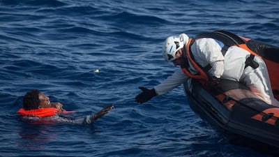 A rescuer from the Migrant Offshore Aid Station ‘Phoenix’ vessel reaches to pull a man out of the Mediterranean Sea off Lampedusa, Italy. Getty Images