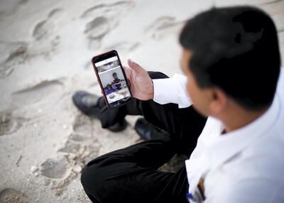 Syed Mohammed looks at a photo of his children in Pakistan. Reem Mohammed / The National
