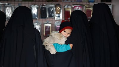A child is held by a woman inside a shop in Al Hol camp, Syria, January 8, 2020. REUTERS
