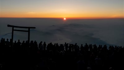 People gather around a torii gate as they watch the sunrise from the summit of Mount Fuji. AP
