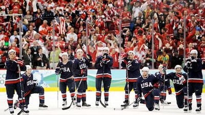 The dejected US team players look on as the Canadian supporters rejoice on the overtime winning goal.