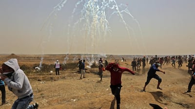 Palestinians take cover from tear gas smoke during clashes with Israeli security forces near the border fence with Israel, east of Gaza City in the central Gaza Strip on April 13. Mahmud Hams / AFP Photo