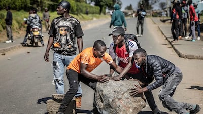 Protesters roll a large stone as they attempt to block a main road. AFP