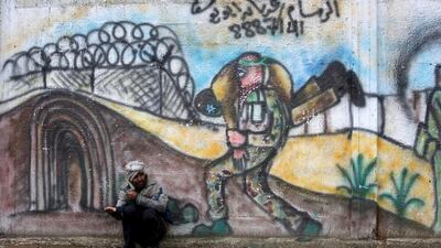 A Palestinian man begs for money as he sits in front of a mural on a street in Khan Younis in the southern Gaza Strip. Ibraheem Abu Mustafa / Reuters
