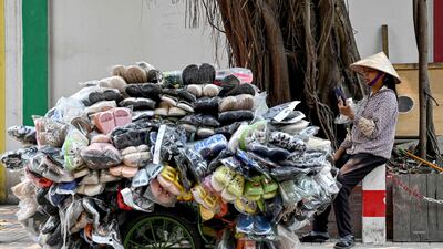 A shoe street seller uses her phone as she waits for customers in Hanoi. AFP