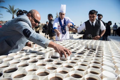 Helpers arrange cups with black coffee and milk coffee to create a mosaic depicting the ancient Egyptian pharaoh Tutankhamun's death mask. EPA