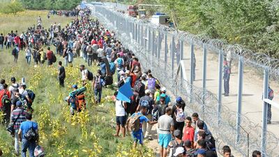 Migrants walking along the razor wire fence at the Serbia-Hungary borde on September 15, 2015. Hungary has sealed the last gap in the barricade along its border with Serbia, closing the passage to thousands of refugees and migrants still waiting on the other side. Darko Dozet/EPA