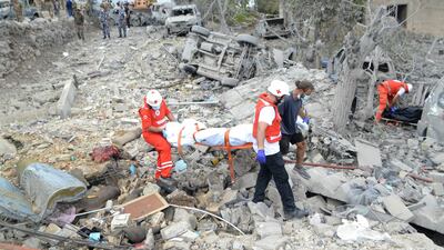 Paramedics carry a body unearthed from the rubble at the site of an Israeli air strike in the northern Lebanese village of Aito. AFP