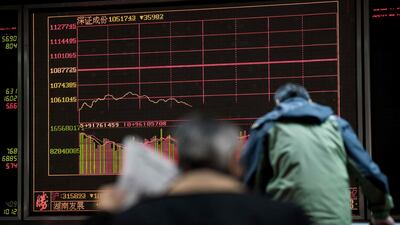 A man (reads a newspaper while keeping an eye on stock price movements at a securities company in Beijing on March 23, 2018. Hong Kong and mainland Chinese stocks plunged at open on March 23 on growing fears of a global trade war after Donald Trump imposed billions of dollars of tariffs on Chinese imports and Beijing drew up a list of retaliatory measures. / AFP PHOTO / NICOLAS ASFOURI