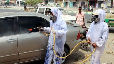 Yemeni sanitation workers, wearing protective gear, spray disinfectant in a neighbourhood in the northern Hajjah province on May 31, 2020, amid the coronavirus pandemic. AFP