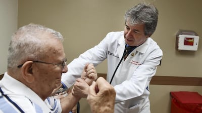 A cardiologist checks the arm strength of a patient during a consultation. Getty Images