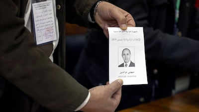 An election official holds a ballot paper showing presidential candidate Azzedine Mihoubi during vote counting at a polling station in Algiers, Algeria. EPA