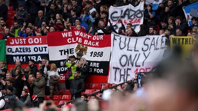 Manchester United fans with banners aimed at the club's owners are seen in the stands before the FA Cup quarter-final match against Fulham at Old Trafford on Sunday March 19, 2023. PA