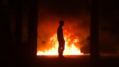 A protester stands near a burning car as police were attacked on the outskirts of Belfast, Northern Ireland. Getty