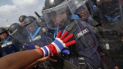 An anti-government protester pushes police officers during clashes near the government house in Bangkok on February 18, 2014. A Thai police officer was killed, and dozens of police and anti-government protesters were wounded in gun battles and clashes Tuesday in the country’s capital, officials and witnesses said. Damir Sagolj / Reuters