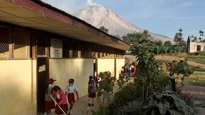 Students prepare before the start of their class as Mount Sinabung is seen in the background, at an elementary school in Beganding, North Sumatra. Ahmad Putra / AP Photo