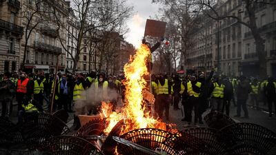 Protesters wearing "yellow vests" stand behind grids set on fire near the Champs Elysees avenue, in Paris. AFP