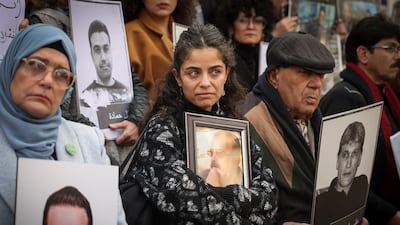 A woman holds a portrait of a missing relative during a protest calling for accountability outside Hijaz train station in Damascus on Friday. AP