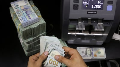 A money vendor counts US banknotes next to Lebanese pounds at a currency exchange in Beirut. Inflation in the country surged to 206 per cent last month. Reuters