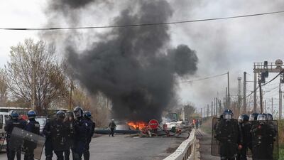 Police and gendarmes work to secure an area blocked by protesters a week after the government pushed a pensions reform through parliament without a vote. AFP