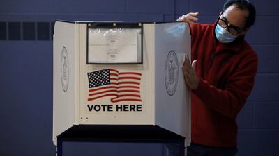 A man sanitizes a privacy booth to fight the spread of coronavirus disease at a polling station opened for early voting at Our Lady Help of Christians in Staten Island, New York City, U.S. REUTERS