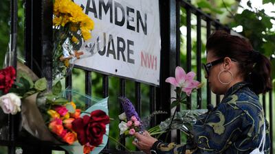 A woman ties flowers to a railing near Winehouse's home, where she was tragically found. AFP