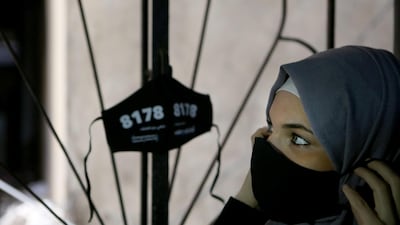 A Palestinian woman looks at a protective mask featuring a hotline number distributed by ABAAD at the Shatila refugee camp in Beirut. ABAAD, a resource centre for gender equality, distributed masks to women and social workers in Beirut, with the 24/7 helpline of the NGO hidden inside the mask. Many women who are on the frontline, providing safety to their families and their surroundings, are still at risk of sexual harassment, abuse and gender-based violence. AFP