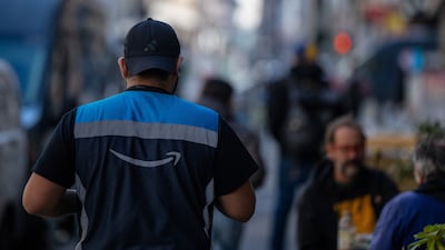 An Amazon employee delivers packages in downtown San Francisco, California. The company plans a new round of corporate job cuts as part of a broader effort to streamline operations. Reuters