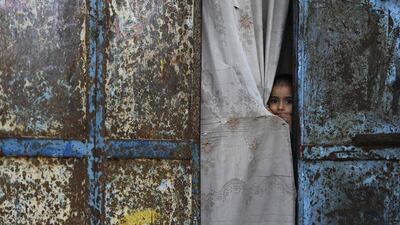A Palestinian girl peers from the door of her home as mourners gather for the funeral of a fisherman in Gaza City. Mohammed Abed / AFP Photo