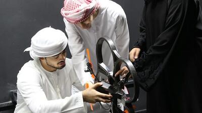 (From left) Ali Al Nuwais, 21, Ibraheem Al Ali, 23 and Fatima Al Hameli, 21, all aerospace engineering students at Khalifa University, check out a drone in their new space lab on Wednesday, October 7, 2015, in Abu Dhabi. Delores Johnson / The National