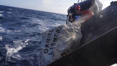 A boulder with Daniel Lismore's name on it is lowered into the sea. Photo: Greenpeace