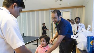 Anil Moolchandani, his son Kavish, and wife Sapna regularly give out food and phone cards to the laborer's in their area during Ramadan. Antonie Robertson / The National