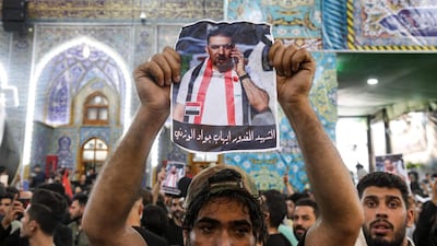 A mourner holds up a poster showing assassinated Iraqi anti-government activist Ihab Al Wazni during his funeral at the Imam Hussein Shrine in the central holy shrine city of Karbala on May 9, 2021. AFP