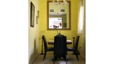 Yellow accent walls and dark furnishings create a cheery mood in the small dining area. Amy Leang / The National