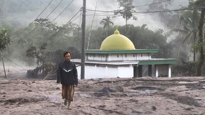 A man walks past a mosque partially covered in volcanic ash from the eruption of Mount Semeru in Kajar Kuning village. AP