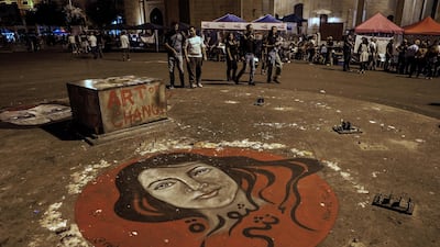 Lebanese protesters walk next to a grafitti on the ground depicting a portrait of woman with Arabic word that reads 'The Revolution is a Female' during ongoing anti-government protests in downtown Beirut. EPA