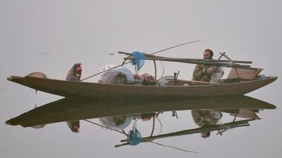 A Kashmiri fisherman looks on his boat on Dal lake during dense fog in Srinagar. Tauseef MUSTAFA / AFP