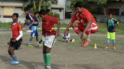 'If I score a goal for one team, I am hired to play for another team and I earn a little money,' says Arka Dey (jumping). 'One of my neighbours has promised me to buy me a nice kit and good pair of shoes before I leave.' Dibyangshu Sarkar / AFP